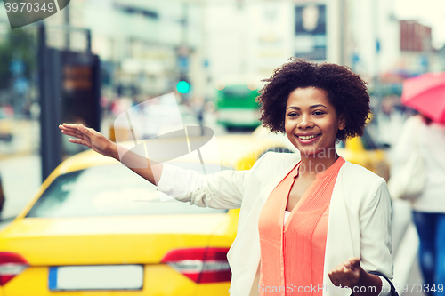 Image of happy african woman catching taxi