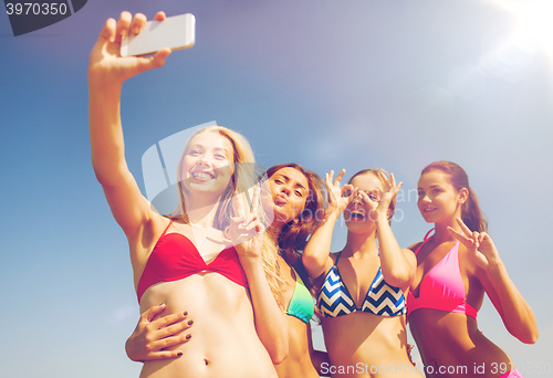 Image of group of smiling women making selfie on beach