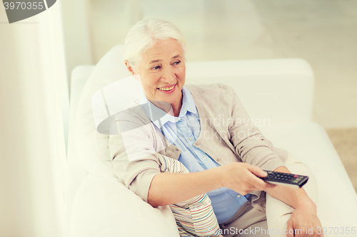 Image of happy senior woman watching tv at home