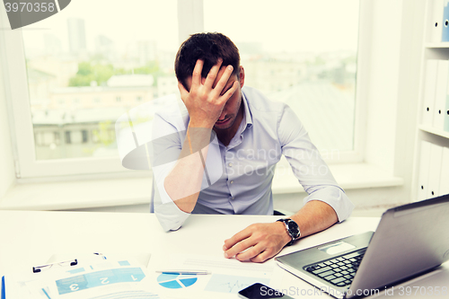 Image of businessman with laptop and papers in office