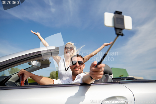 Image of happy couple in car taking selfie with smartphone