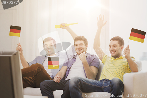 Image of happy male friends with flags and vuvuzela