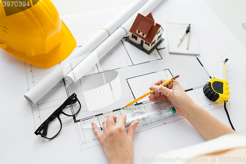 Image of close up of hands with ruler measuring blueprint