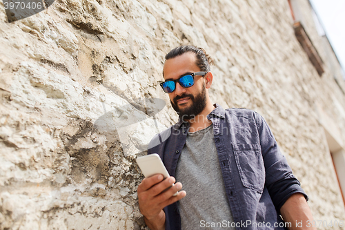 Image of man texting message on smartphone at stone wall