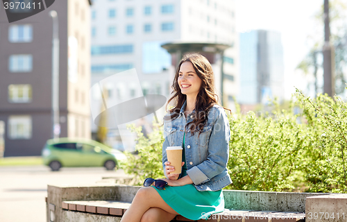 Image of happy young woman drinking coffee on city street