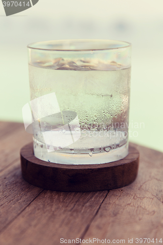 Image of glass of water with ice cubes on table at beach