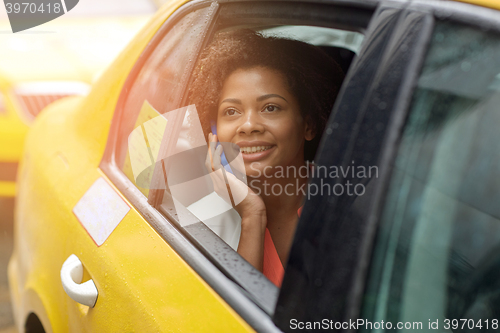 Image of happy african woman calling on smartphone in taxi