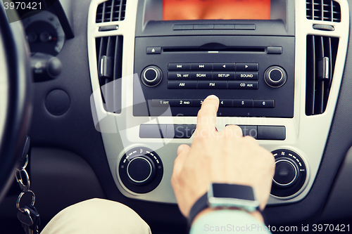 Image of close up of male hand turning on radio in car