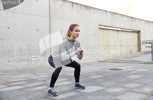 Image of happy woman doing squats and exercising outdoors