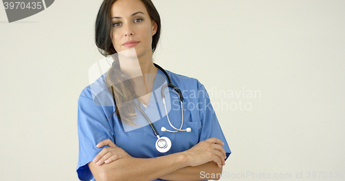 Image of Woman in scrubs crosses arms and smiles at camera