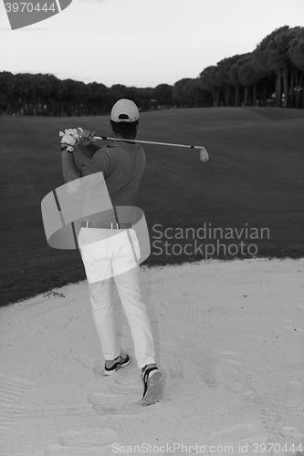 Image of golfer hitting a sand bunker shot on sunset