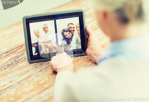 Image of senior woman with family photo on tablet pc screen