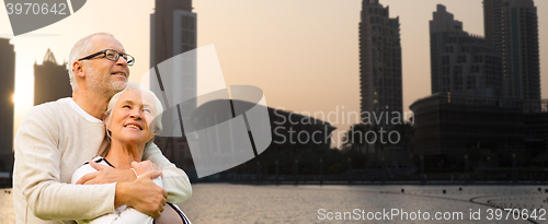 Image of senior couple hugging over dubai city background
