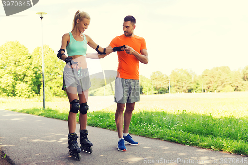 Image of happy couple with roller skates riding outdoors