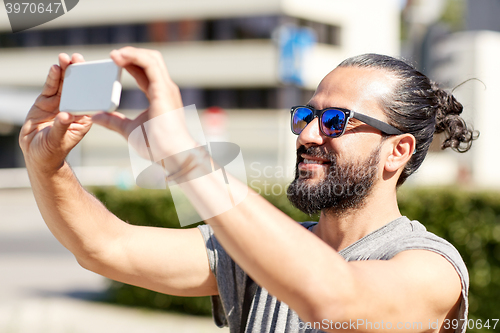 Image of man taking video or selfie by smartphone in city