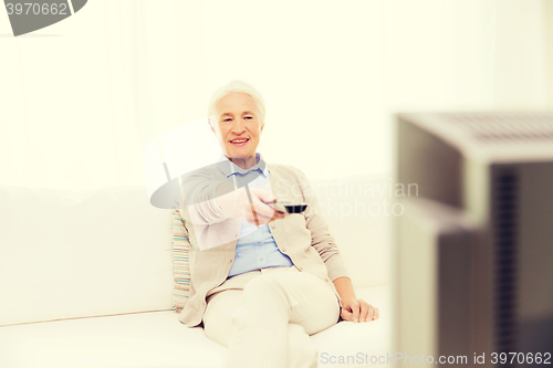 Image of happy senior woman watching tv at home