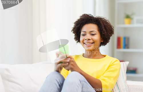 Image of happy african woman with smartphone at home