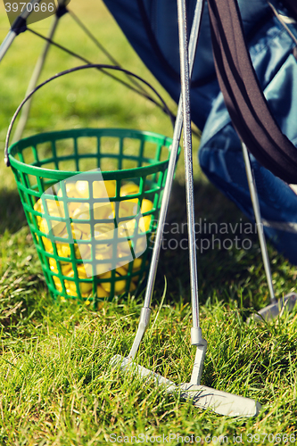 Image of close up of golf club and balls in basket on grass