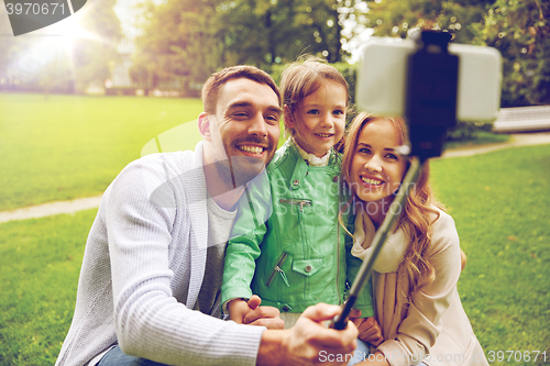 Image of happy family taking selfie by smartphone outdoors