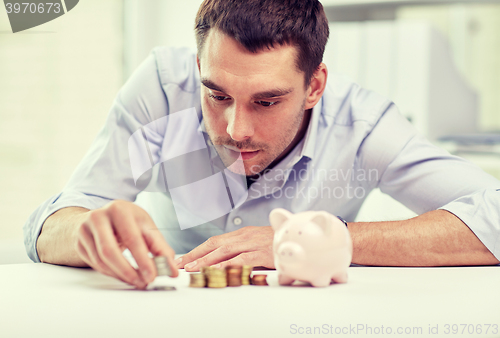 Image of businessman with piggy bank and coins at office