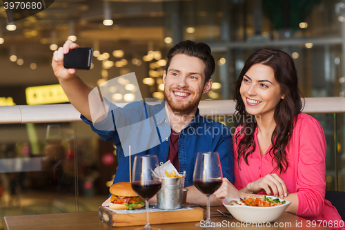 Image of couple taking selfie by smartphone at restaurant