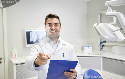 Image of happy dentist pointing to you at dental clinic