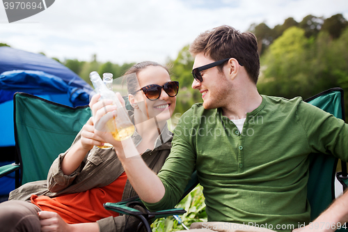 Image of happy couple clinking drinks at campsite tent