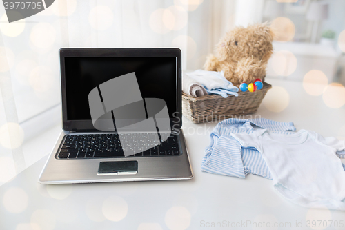 Image of close up of baby clothes, toys and laptop at home