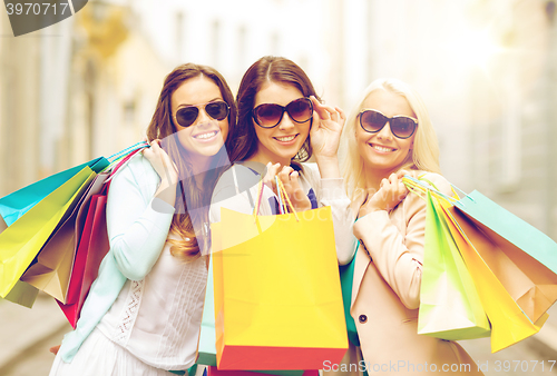 Image of three smiling girls with shopping bags in ctiy