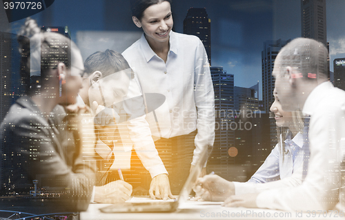 Image of smiling female boss talking to business team