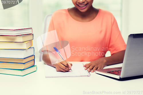 Image of close up of woman with laptop and books at home
