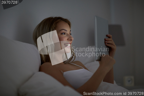 Image of young woman with tablet pc in bed at home bedroom