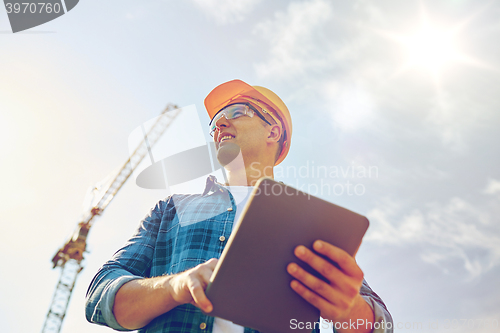 Image of builder in hardhat with tablet pc at construction