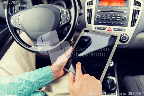 Image of close up of young man with tablet pc driving car