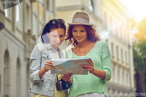 Image of smiling teenage girls with map and camera outdoors