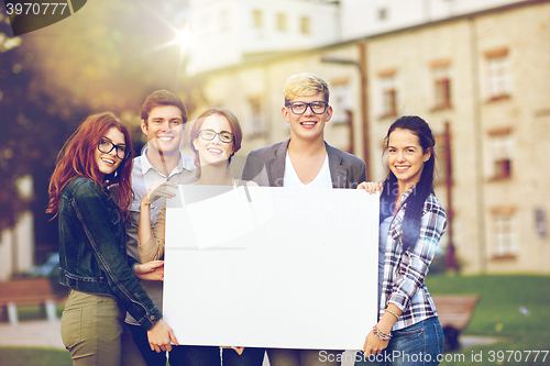 Image of happy teenage students holding white blank board