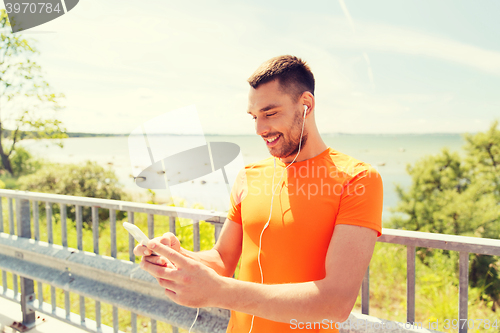 Image of smiling young man with smartphone and earphones