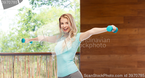 Image of smiling beautiful young sporty woman with dumbbell