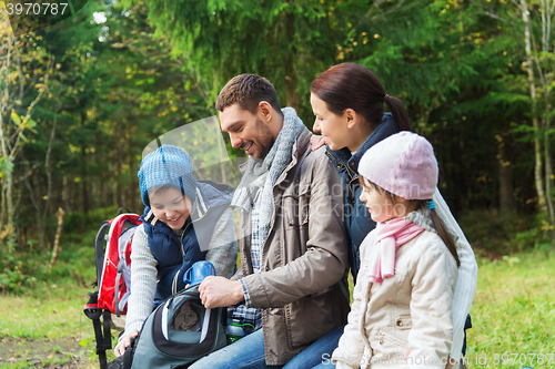 Image of happy family with backpacks and thermos at camp