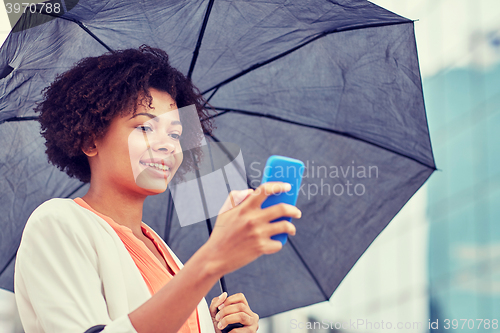 Image of businesswoman with umbrella texting on smartphone