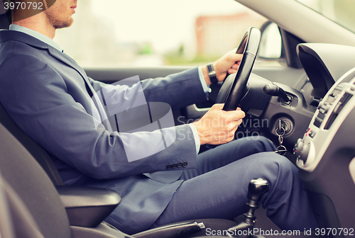 Image of close up of young man in suit driving car