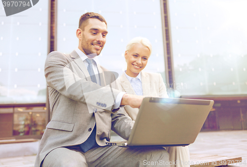 Image of smiling businesspeople with laptop outdoors