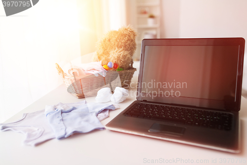 Image of close up of baby clothes, toys and laptop at home
