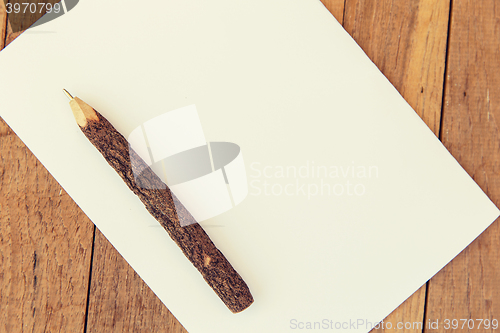 Image of white blank paper sheet with wooden pen on table 