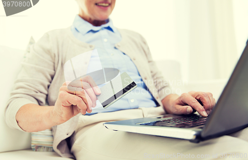 Image of senior woman with laptop and credit card at home