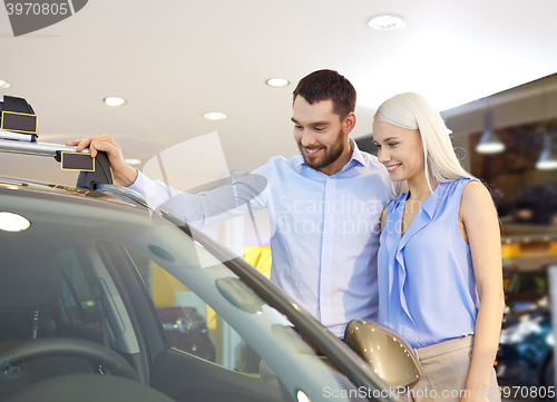 Image of happy couple buying car in auto show or salon