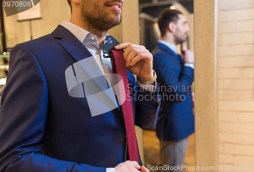 Image of close up of man trying tie on at mirror