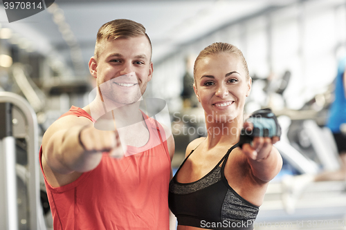 Image of happy man and woman pointing finger to you in gym