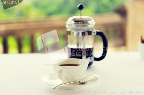 Image of cup of coffee and french press on table 