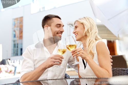 Image of happy couple drinking wine at open-air restaurant